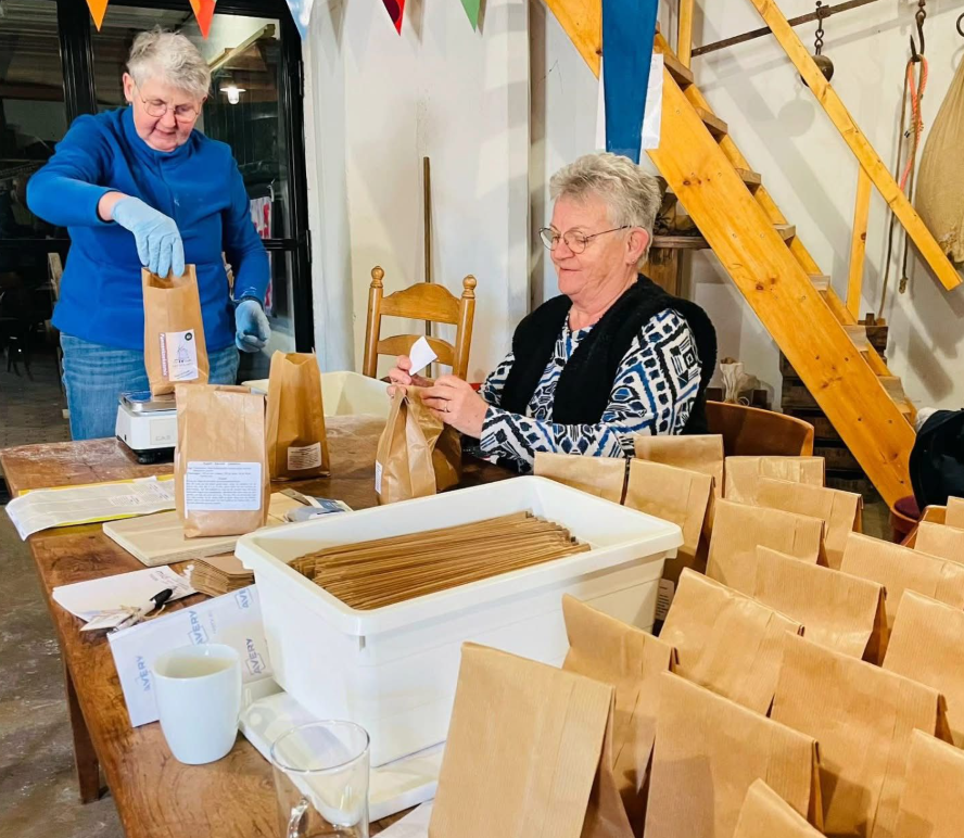 Twee vrijwilligers vullen de zakjes met pannenkoekenmeel.